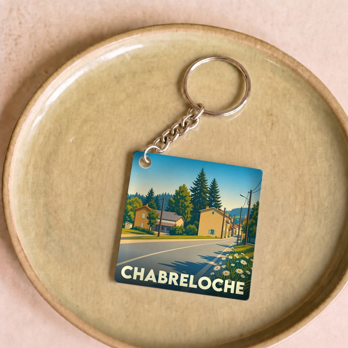 Porte-clés souvenir de la ville de Chabreloche avec une illustration stylisée d'un paysage urbain.