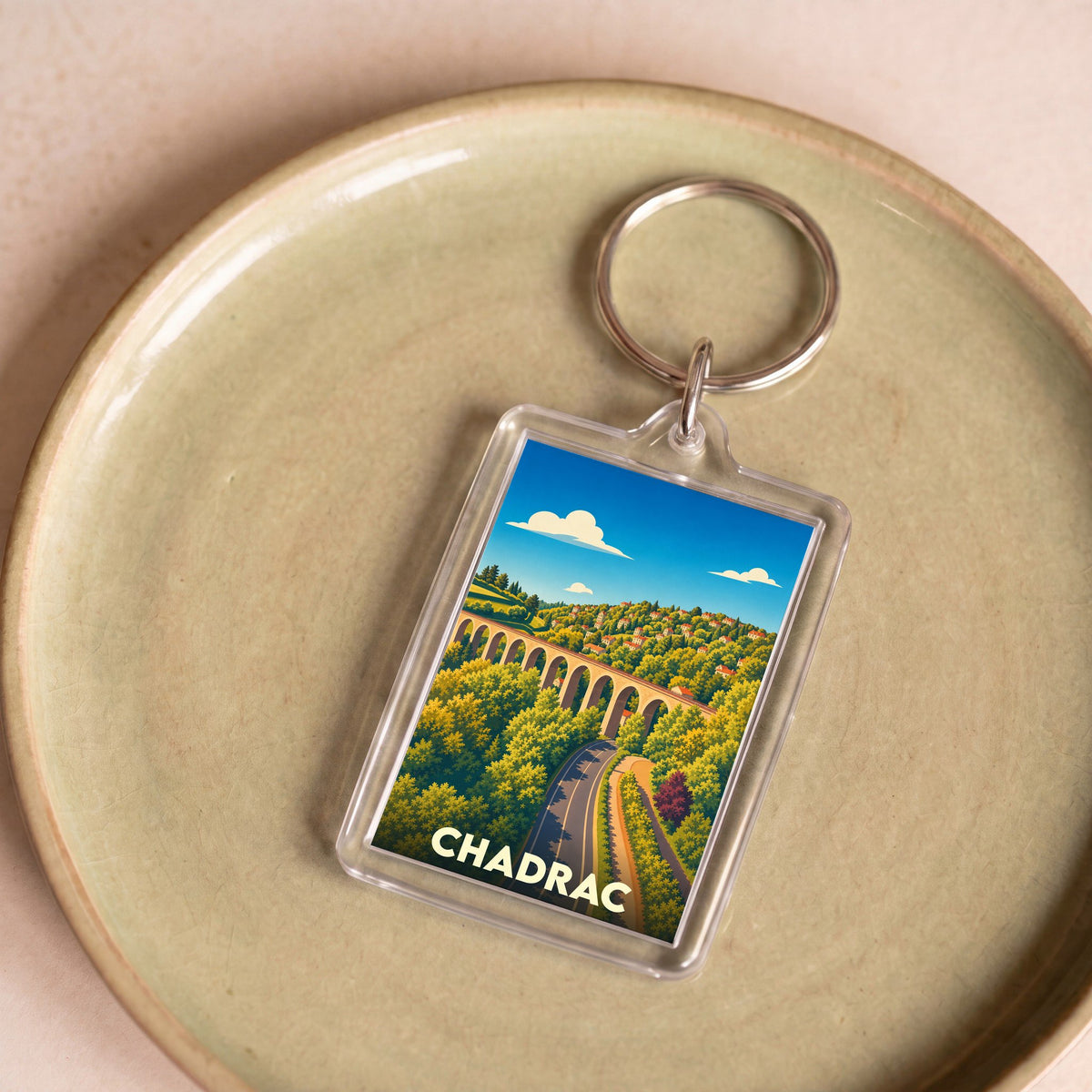 Porte-clés souvenir de la ville de Chadrac avec une illustration stylisée d'un viaduc et de paysages verdoyants.