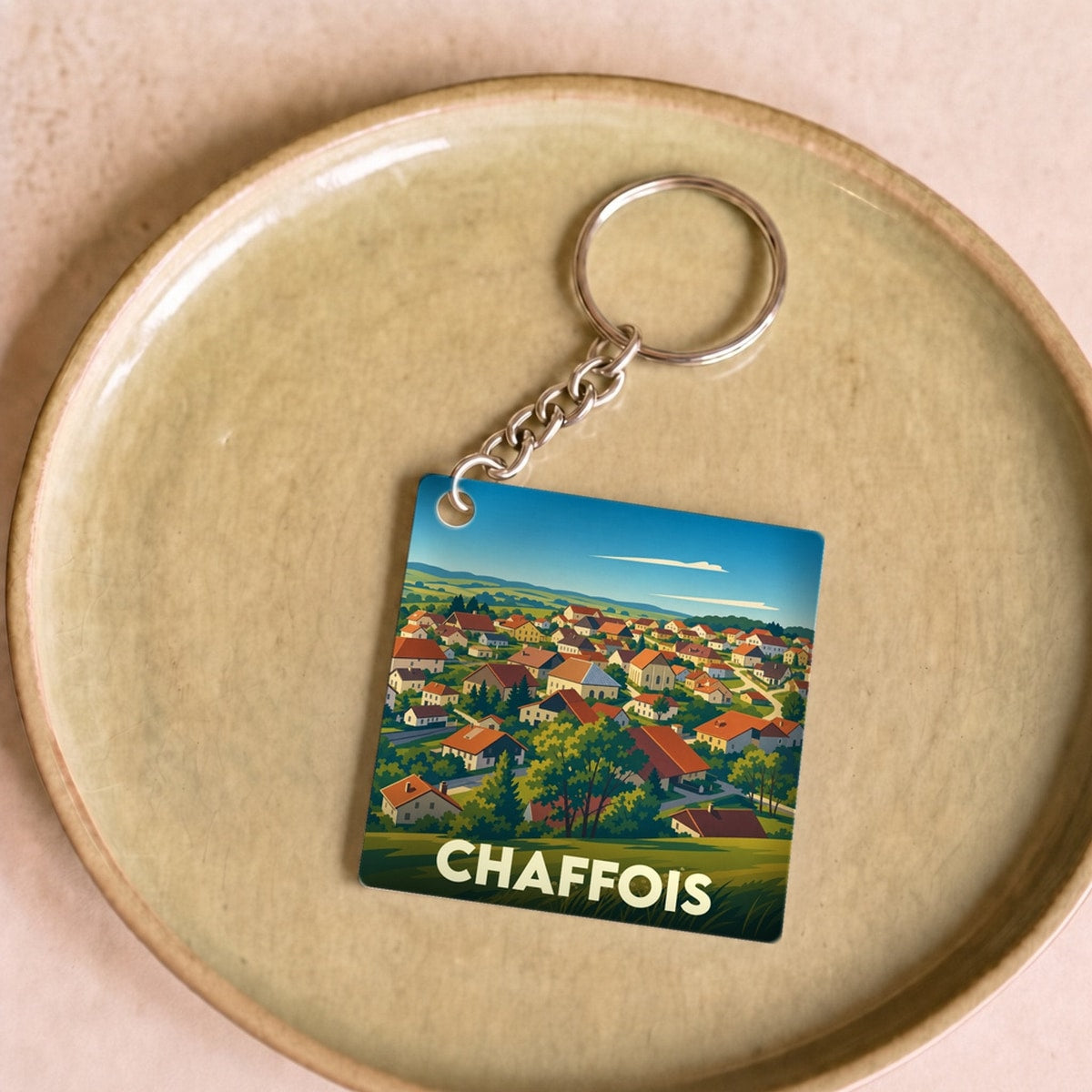 Porte-clés souvenir de la ville de Chaffois avec une illustration stylisée de ses paysages.
