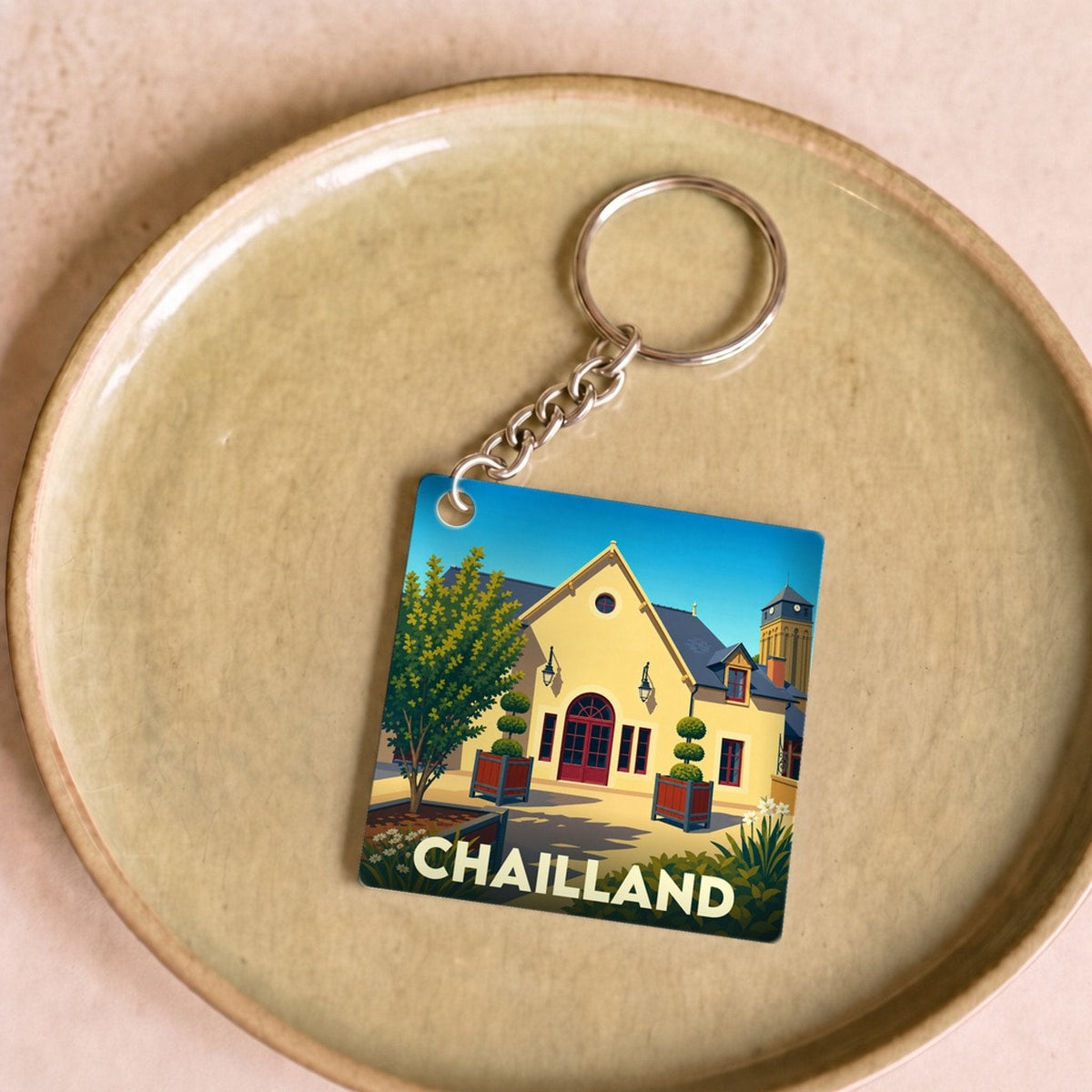 Porte-clés souvenir de la ville de Chailland avec une illustration stylisée.