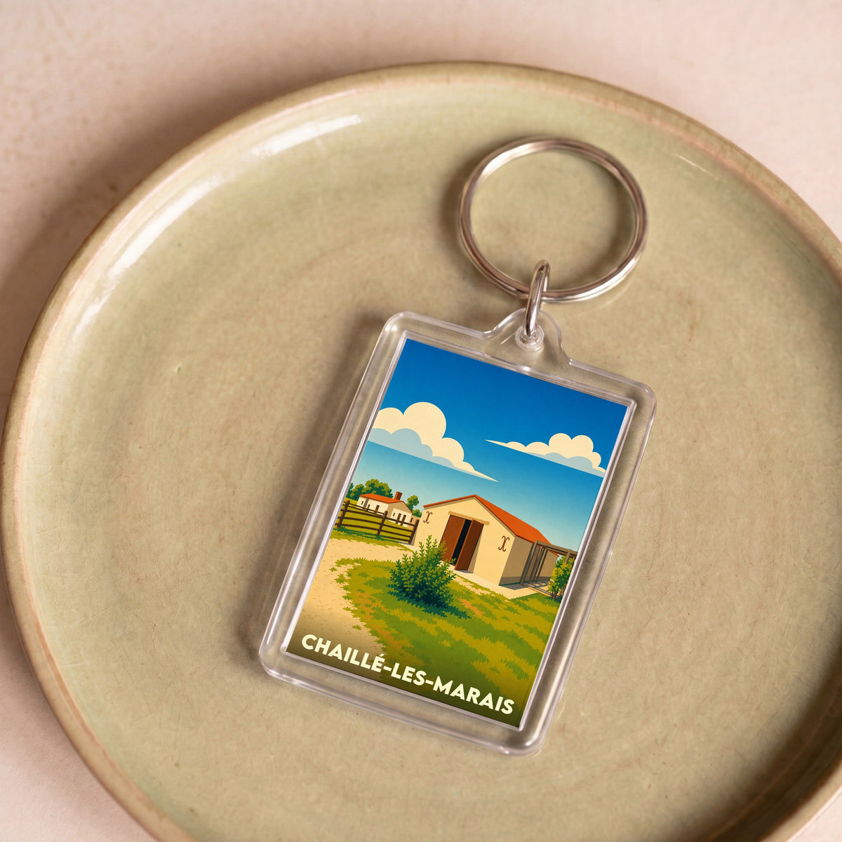Porte-clés souvenir de la ville de Chaillé-les-Marais avec une illustration stylisée de paysages ruraux.