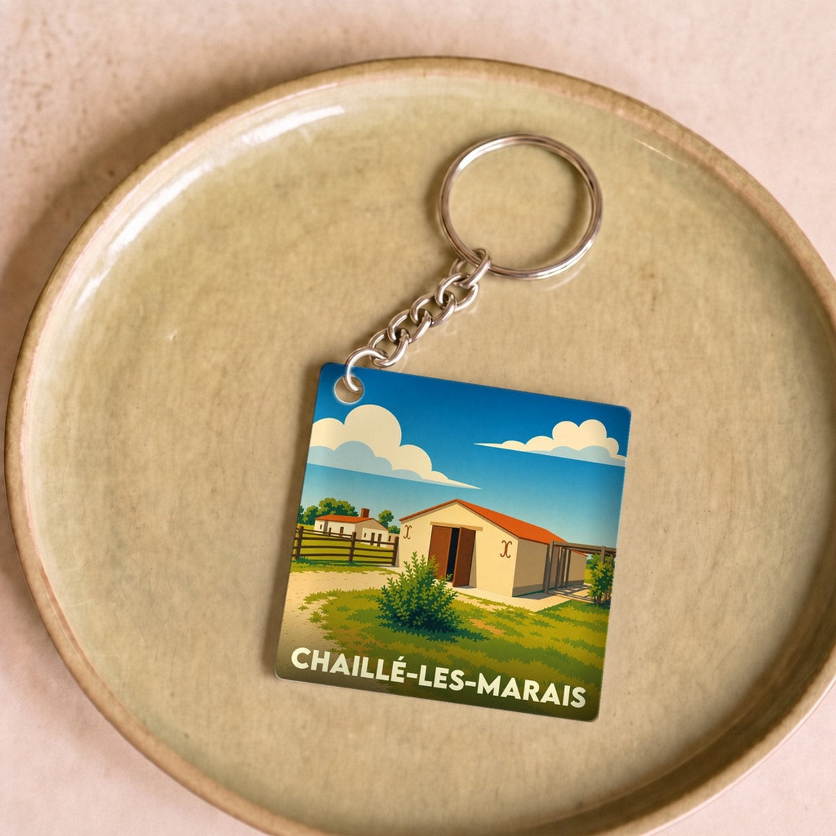 Porte-clés souvenir de la ville de Chaillé-les-Marais avec une illustration stylisée de paysages ruraux.
