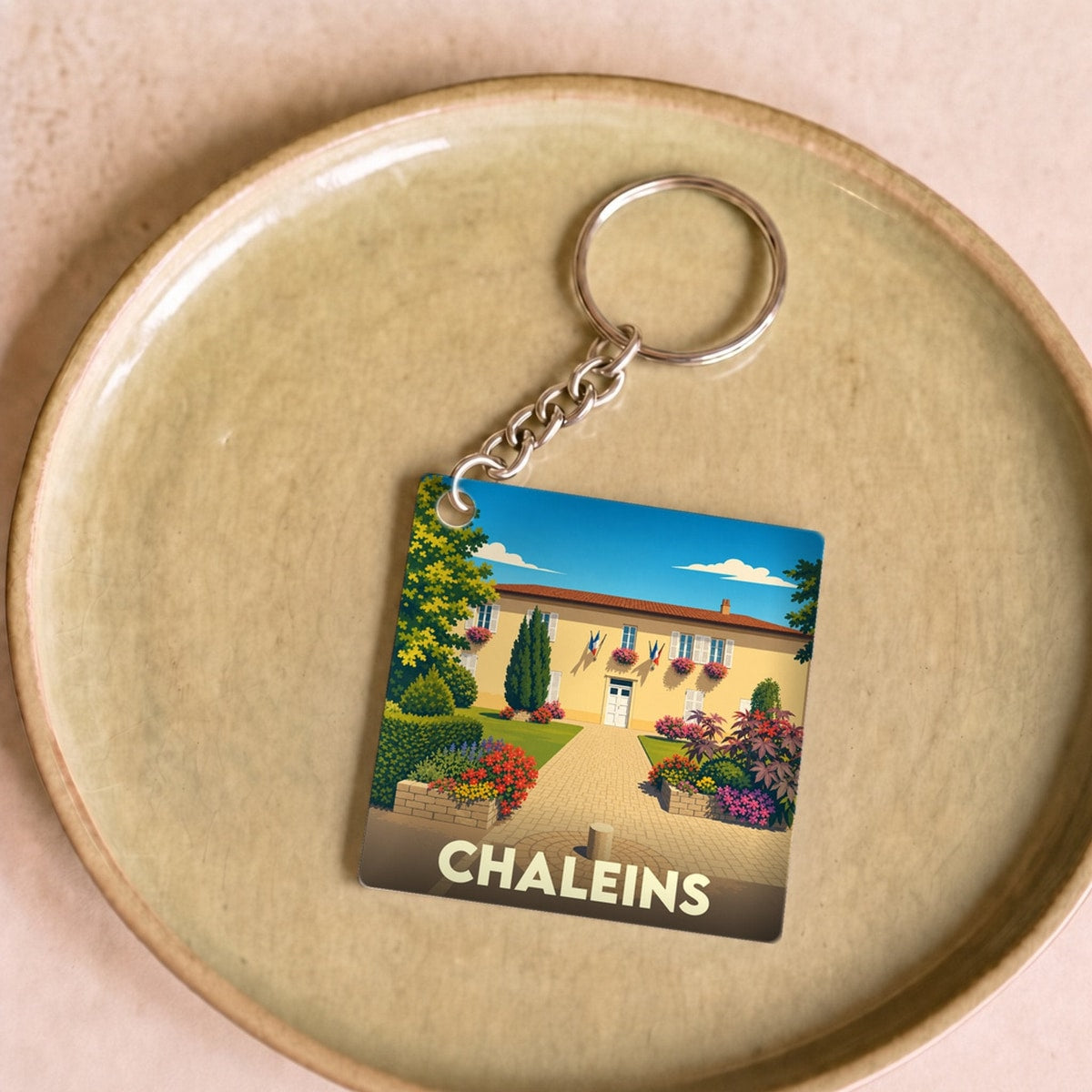 Porte-clés souvenir de la ville de Chaleins avec une illustration stylisée de sa mairie fleurie.