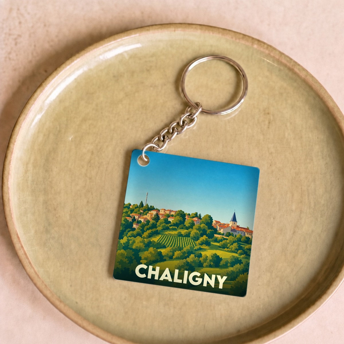 Porte-clés souvenir de la ville de Chaligny avec une illustration stylisée de son paysage vallonné.