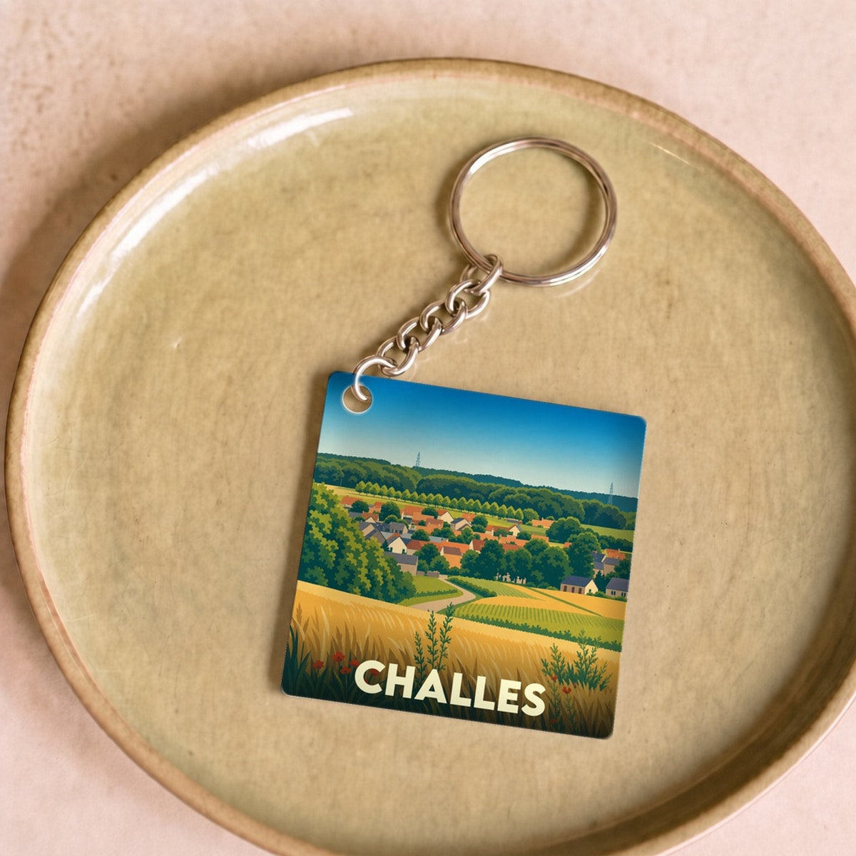 Porte-clés souvenir de la ville de Challes avec une illustration stylisée de son paysage rural.
