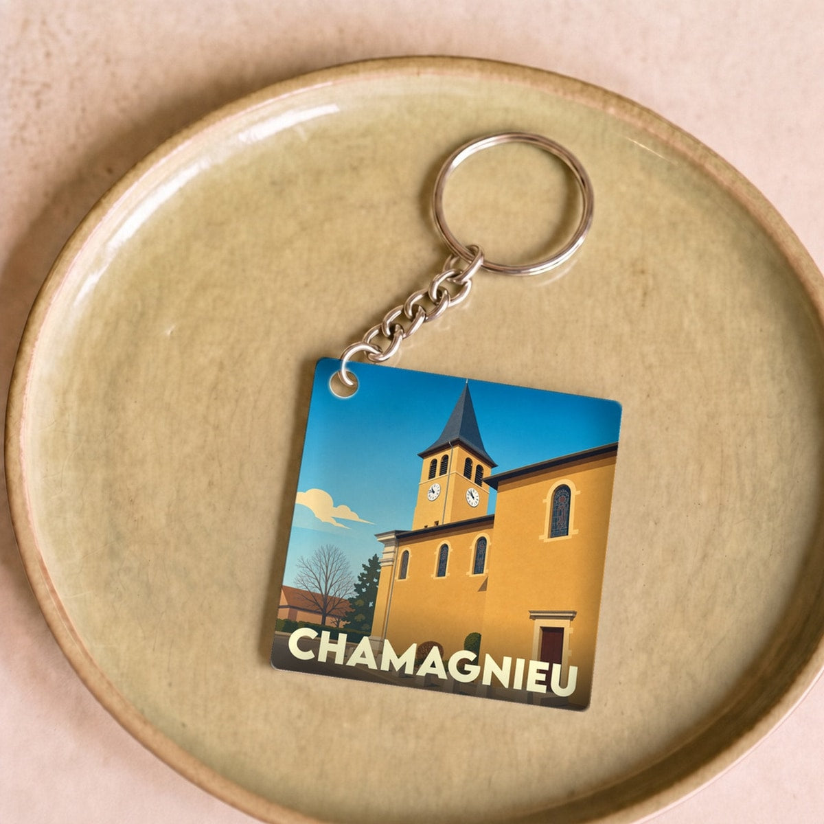 Porte-clés souvenir de la ville de Chamagnieu avec une illustration stylisée de son église.