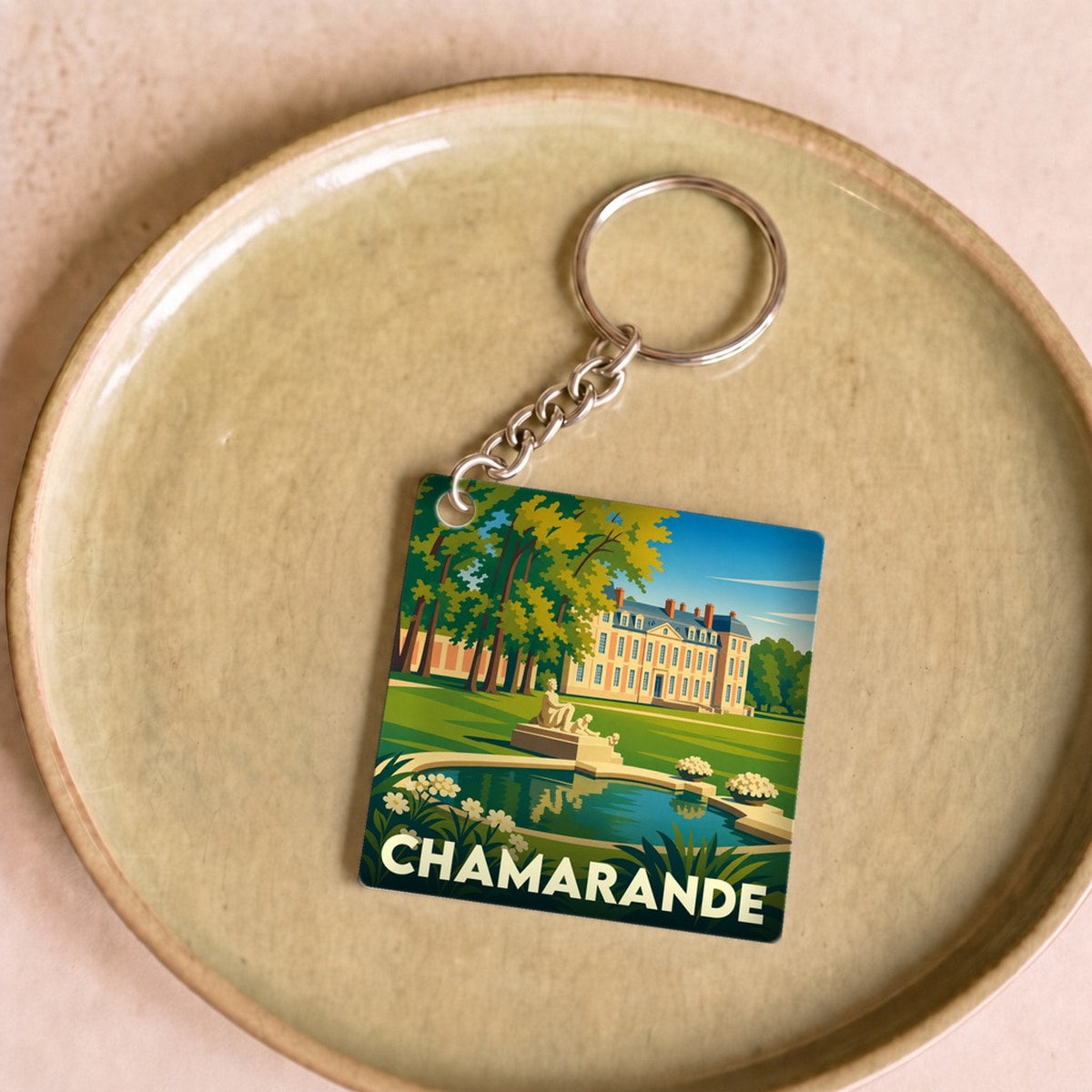 Porte-clés souvenir de la ville de Chamarande avec une illustration stylisée de son château et de son parc.