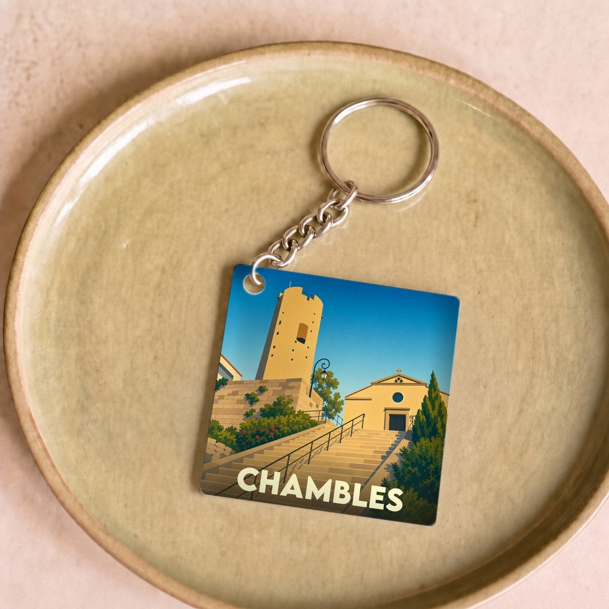 Porte-clés souvenir de la ville de Chambles avec une illustration stylisée de son patrimoine.
