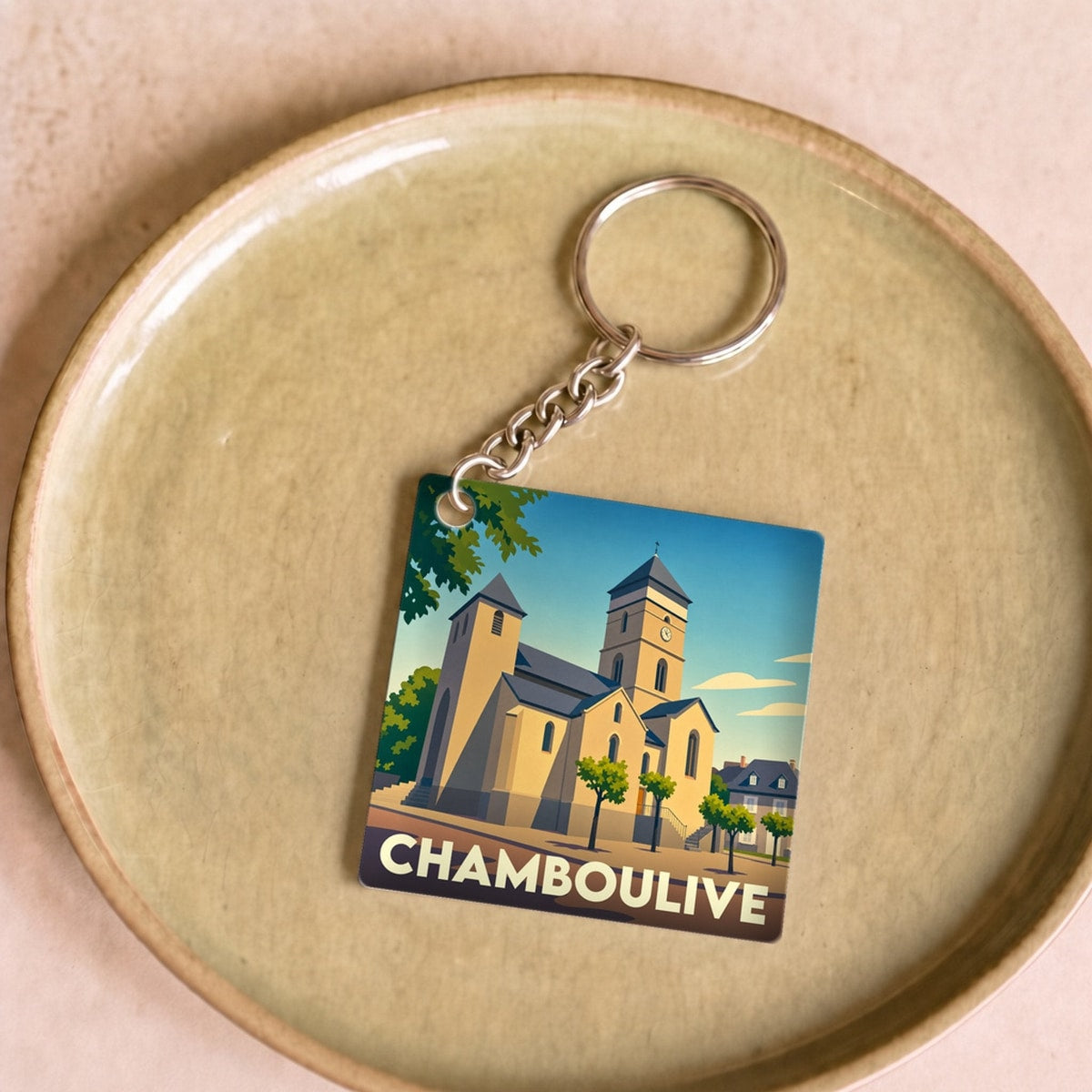 Porte-clés souvenir de la ville de Chamboulive avec une illustration stylisée de son église.
