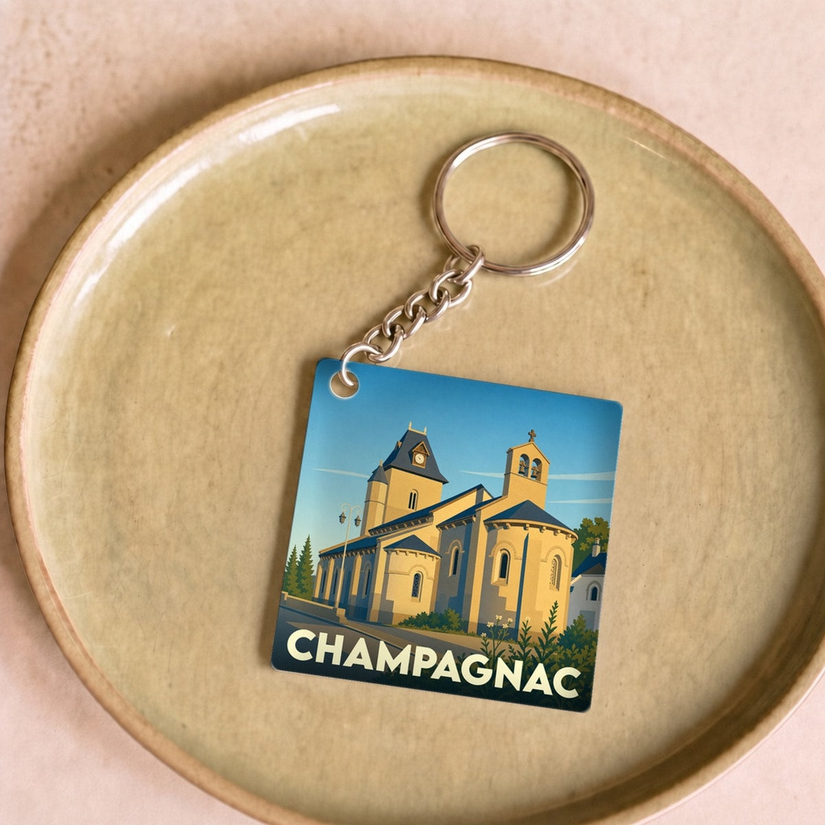 Porte-clés souvenir de la ville de Champagnac avec une illustration stylisée de son église.