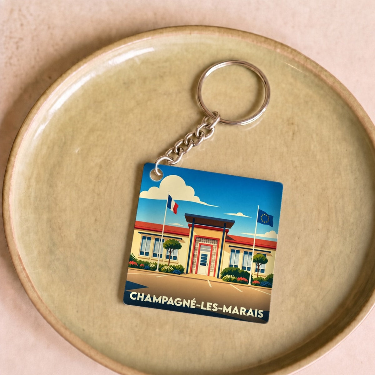 Porte-clés souvenir de la ville de Champagné-les-Marais avec une illustration stylisée de sa mairie.
