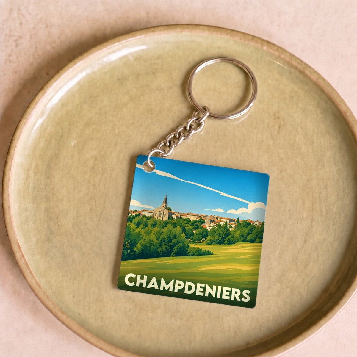 Porte-clés souvenir de la ville de Champdeniers avec une illustration stylisée de son paysage.