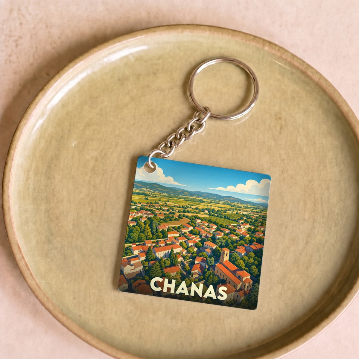 Porte-clés souvenir de la ville de Chanas avec une illustration stylisée d'un paysage urbain et rural.