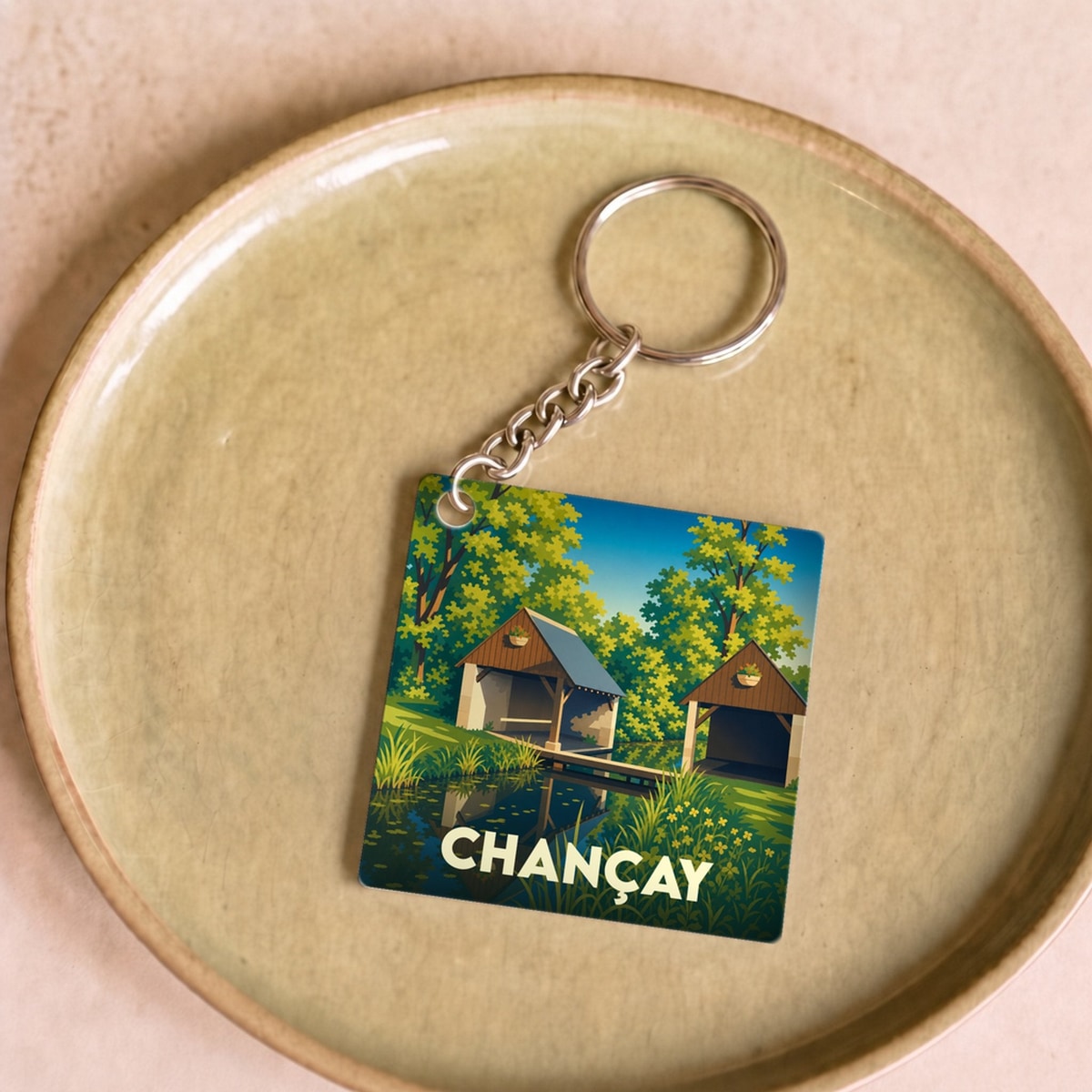 Porte-clés souvenir de la ville de Chançay avec une illustration stylisée de son paysage.