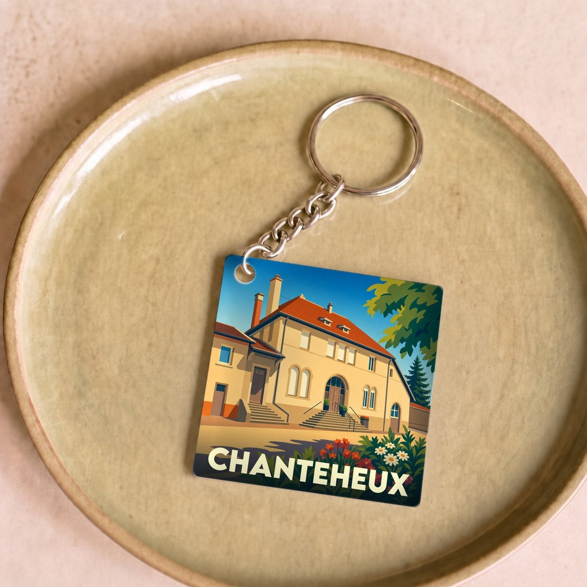 Porte-clés souvenir de la ville de Chanteheux avec une illustration stylisée d'un bâtiment historique.