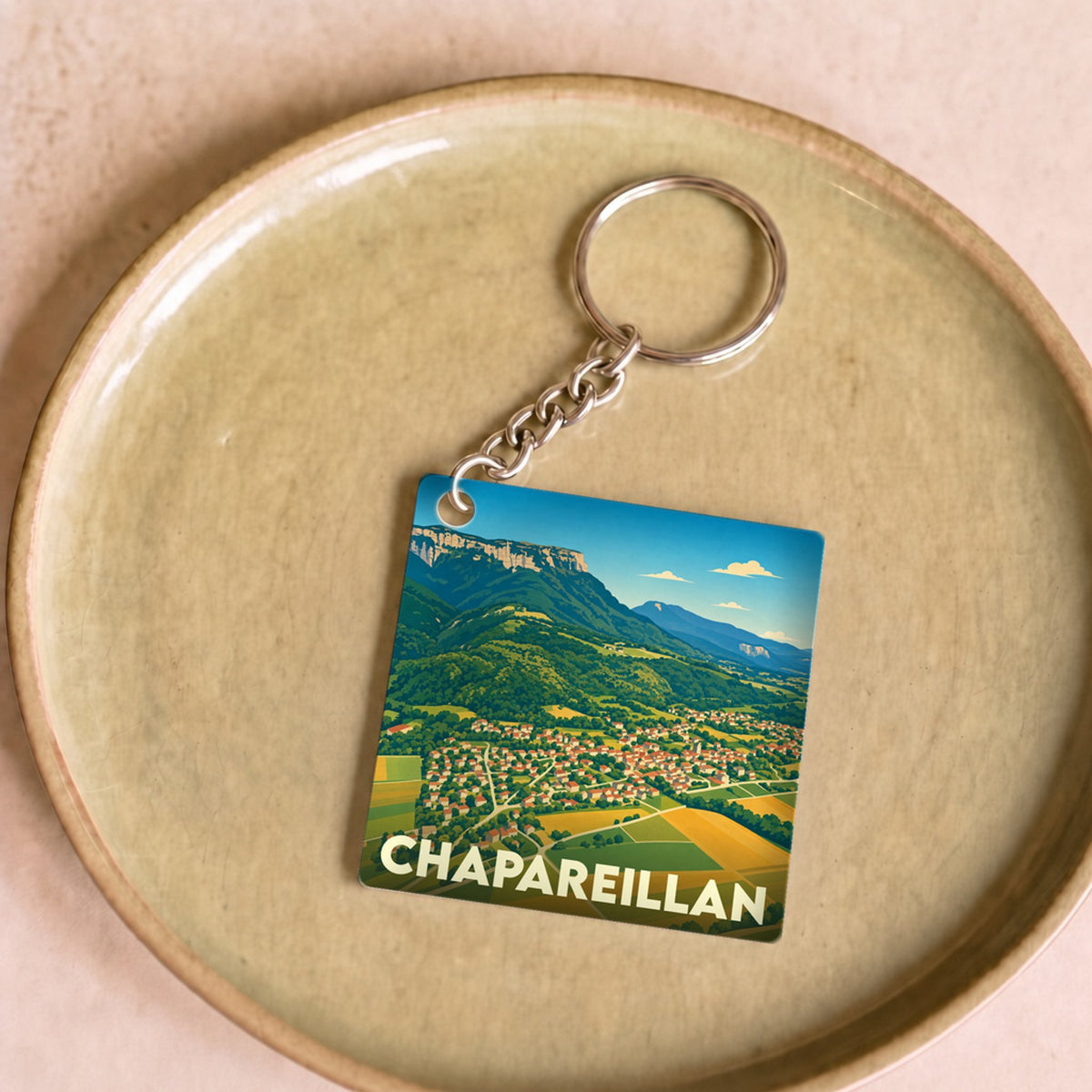 Porte-clés souvenir de la ville de Chapareillan avec une illustration stylisée de son paysage montagneux.