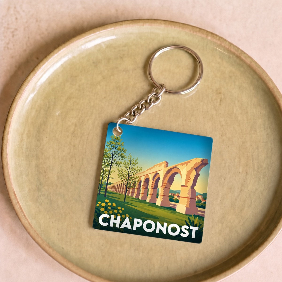 Porte-clés souvenir de la ville de Chaponost avec une illustration stylisée de son aqueduc romain.