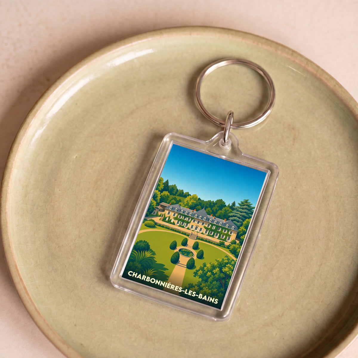 Porte-clés souvenir de la ville de Charbonnières-les-Bains avec une illustration stylisée d'un domaine arboré.