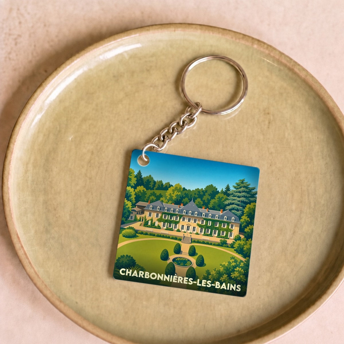 Porte-clés souvenir de la ville de Charbonnières-les-Bains avec une illustration stylisée d'un domaine arboré.