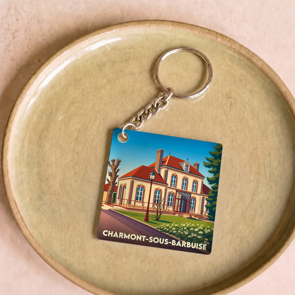 Porte-clés souvenir de la ville de Charmont-sous-Barbuise avec une illustration stylisée d'un bâtiment historique.