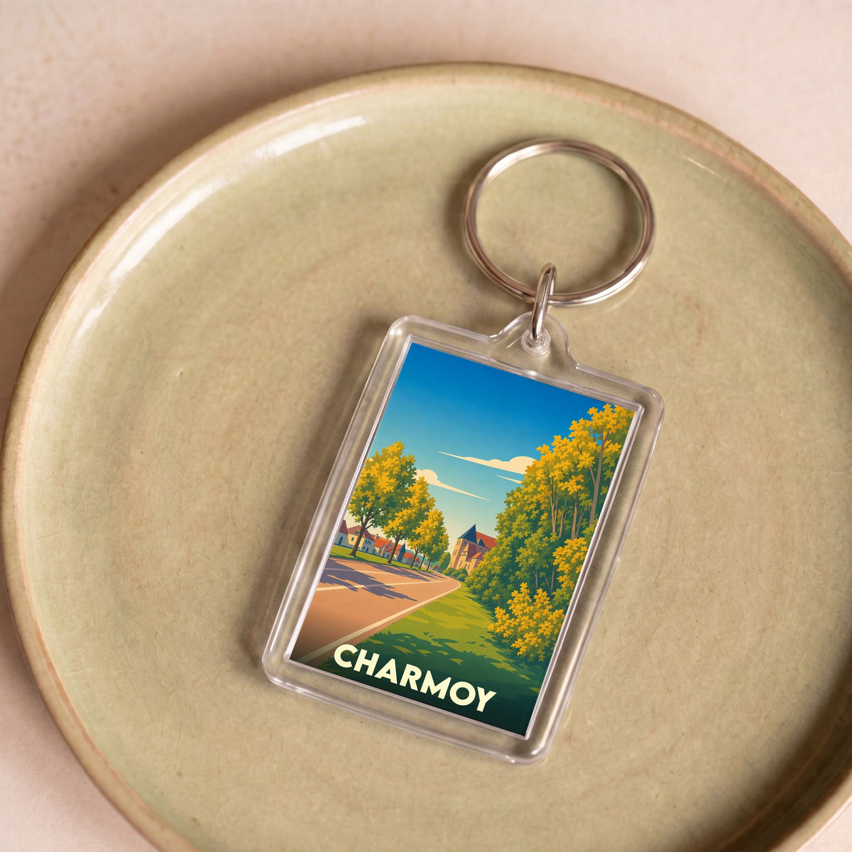 Porte-clés souvenir de la ville de Charmoy avec une illustration stylisée d'un paysage urbain verdoyant.