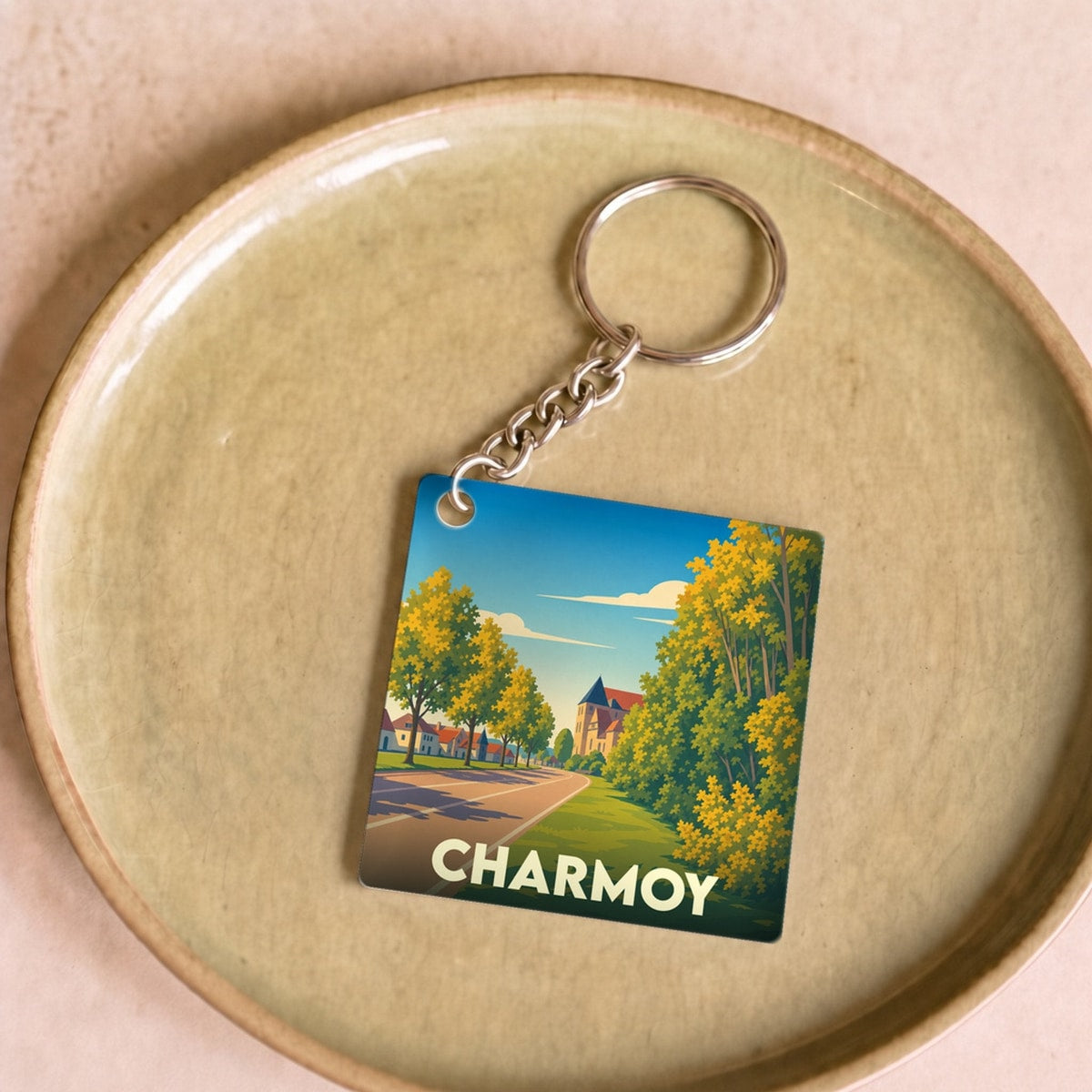 Porte-clés souvenir de la ville de Charmoy avec une illustration stylisée d'un paysage urbain verdoyant.