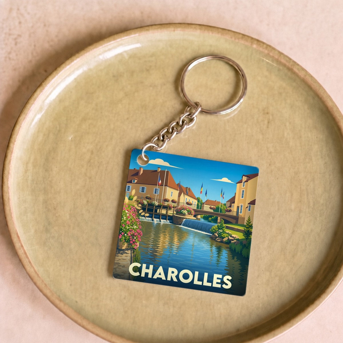 Porte-clés souvenir de la ville de Charolles avec une illustration stylisée d'un paysage urbain au bord de l'eau.