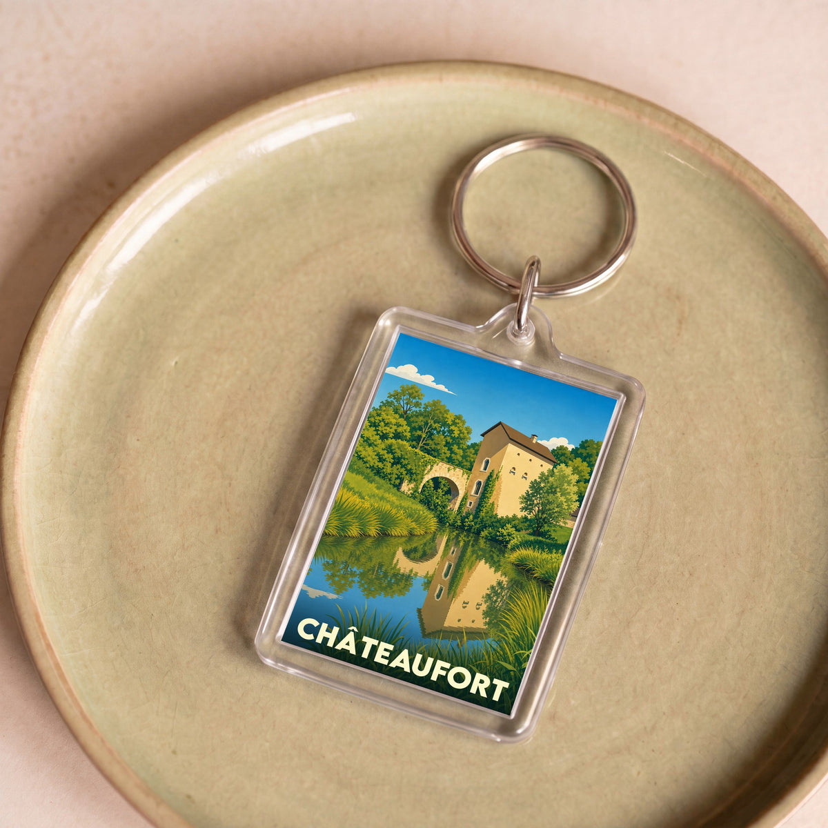 Porte-clés souvenir de la ville de Châteaufort avec une illustration stylisée d'un paysage champêtre.