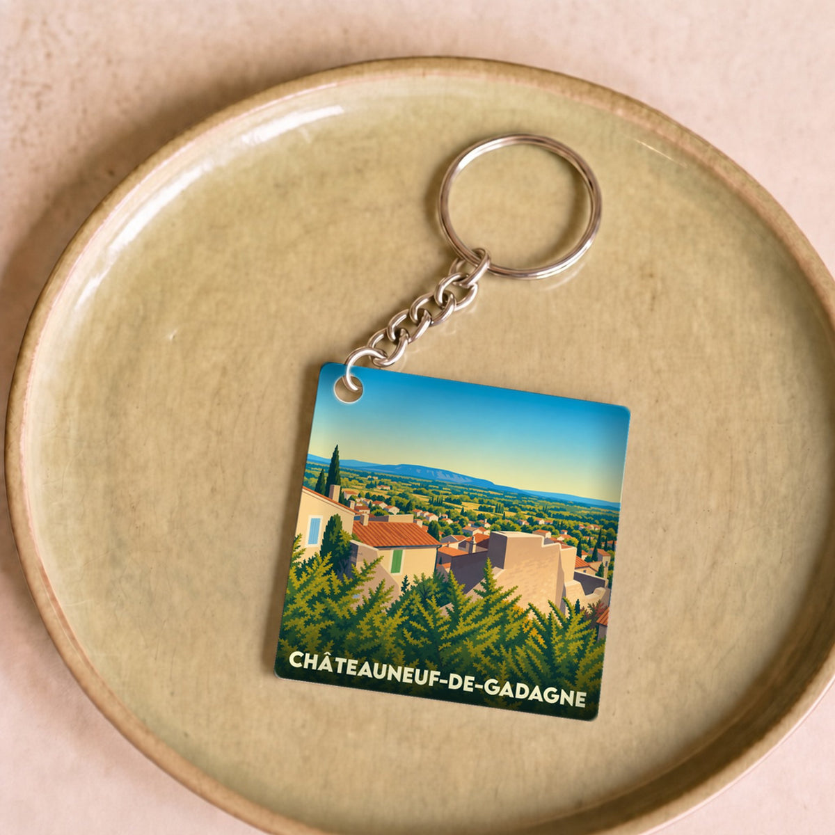 Porte-clés souvenir de la ville de Châteauneuf-de-Gadagne avec une illustration stylisée de son paysage.