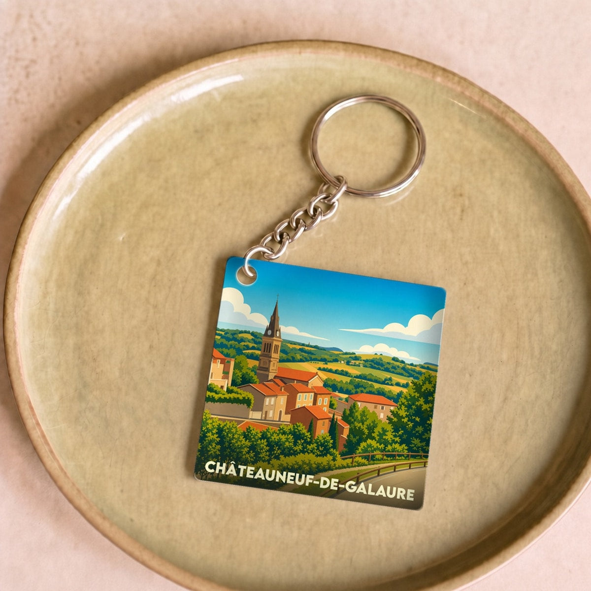 Porte-clés souvenir de la ville de Châteauneuf-de-Galaure avec une illustration stylisée du village.