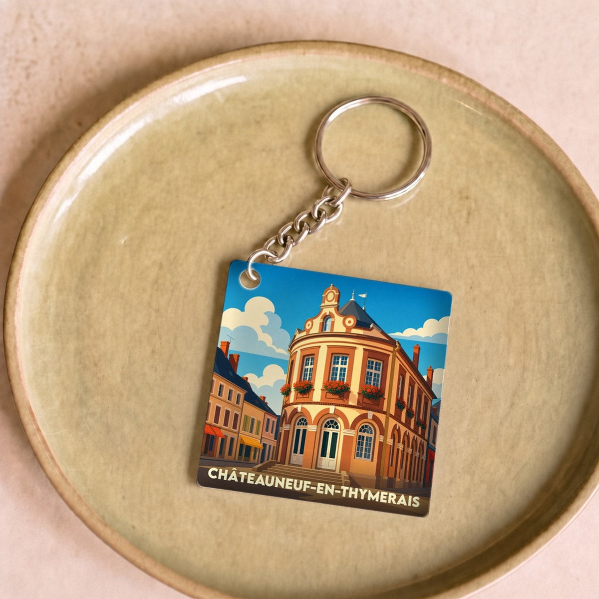 Porte-clés souvenir de la ville de Châteauneuf-en-Thymerais avec une illustration stylisée de son architecture.