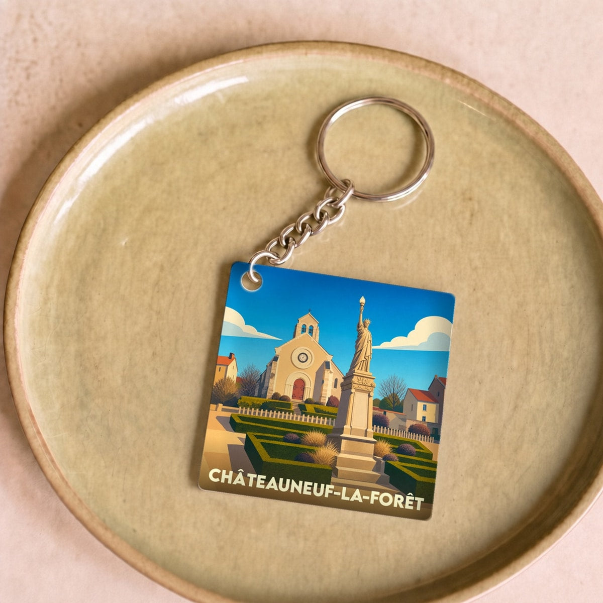 Porte-clés souvenir de la ville de Châteauneuf-la-Forêt avec une illustration stylisée.