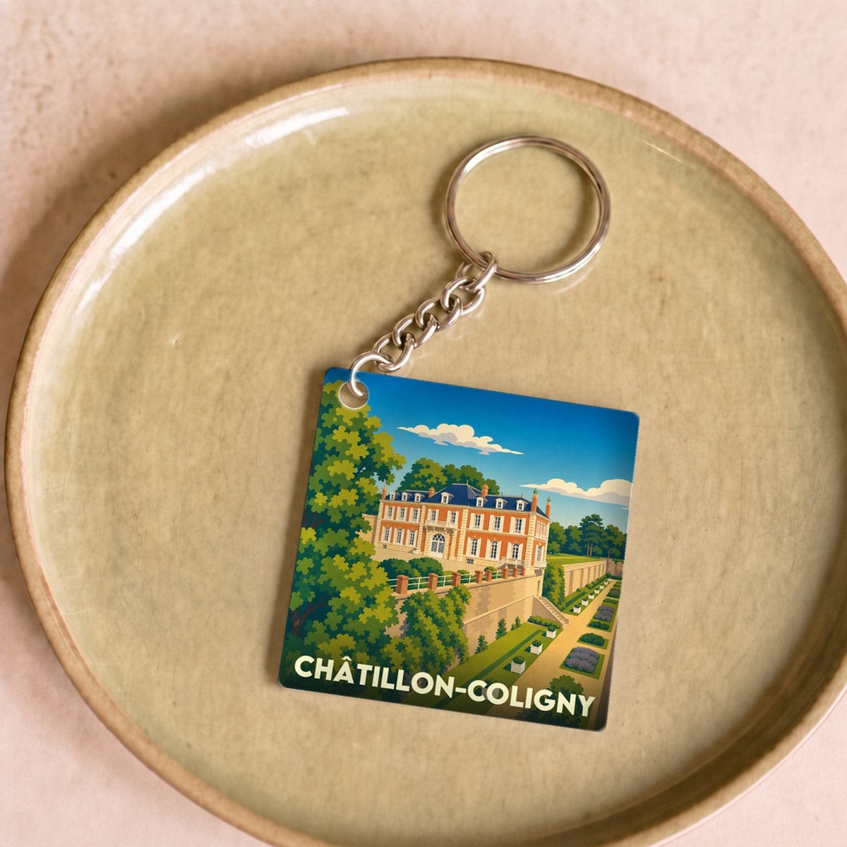 Porte-clés souvenir de la ville de Châtillon-Coligny avec une illustration stylisée de son château et de ses jardins.