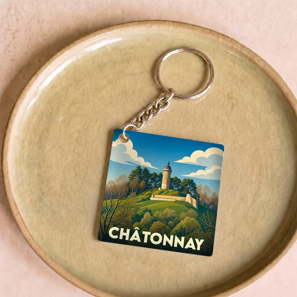 Porte-clés souvenir de la ville de Châtonnay avec une illustration stylisée d'une tour sur une colline boisée.
