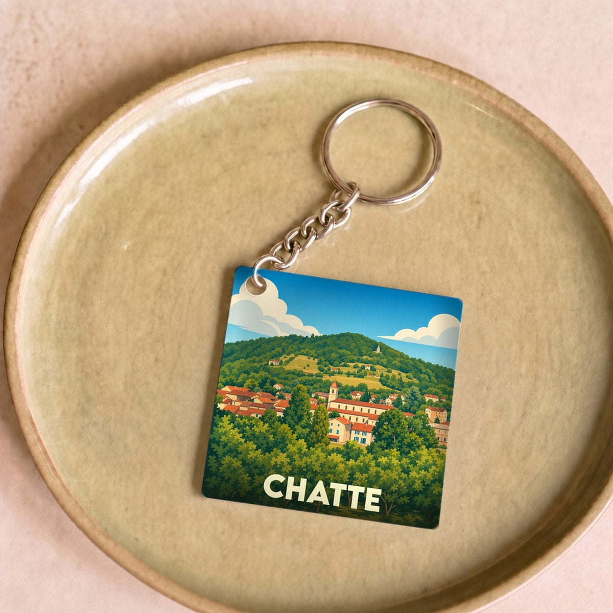 Porte-clés souvenir de la ville de Chatte avec une illustration stylisée d'un paysage verdoyant.