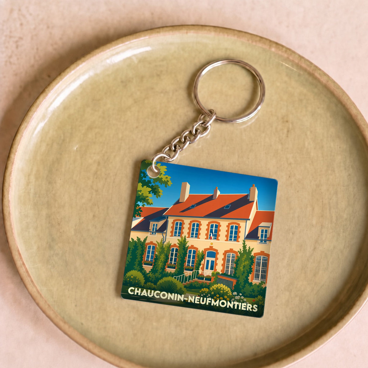 Porte-clés souvenir de la ville de Chauconin-Neufmontiers avec une illustration stylisée d'une grande demeure.
