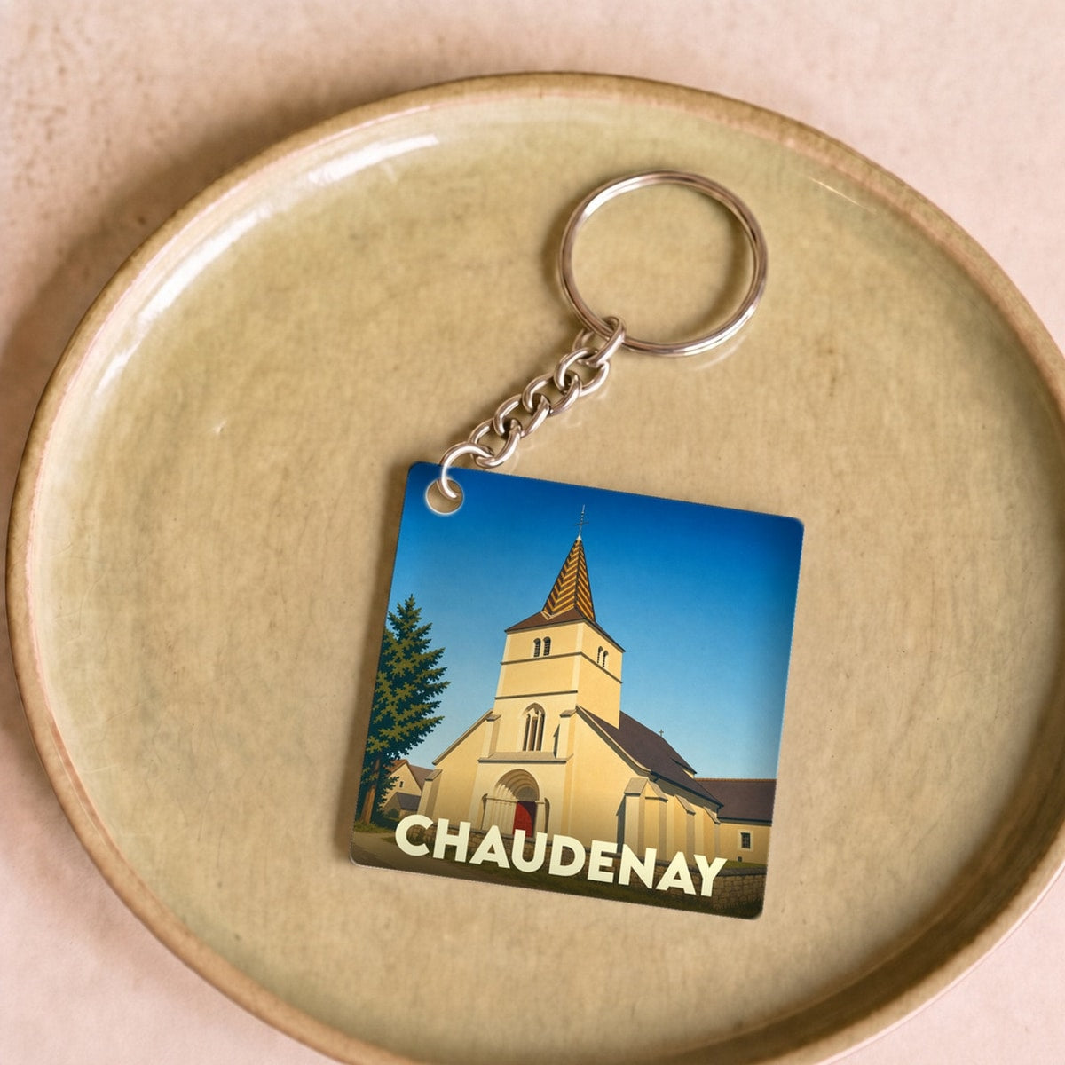 Porte-clés souvenir de la ville de Chaudenay avec une illustration stylisée de son église.