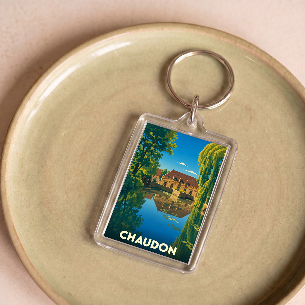 Porte-clés souvenir de la ville de Chaudon avec une illustration stylisée d'un moulin au bord de l'eau.