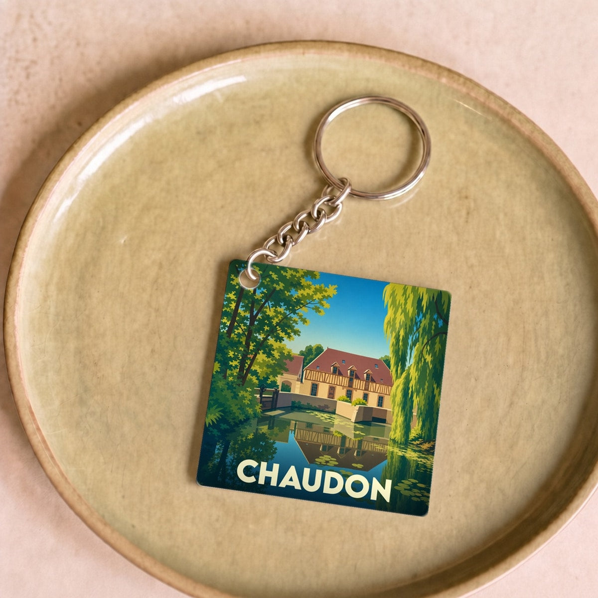 Porte-clés souvenir de la ville de Chaudon avec une illustration stylisée d'un moulin au bord de l'eau.