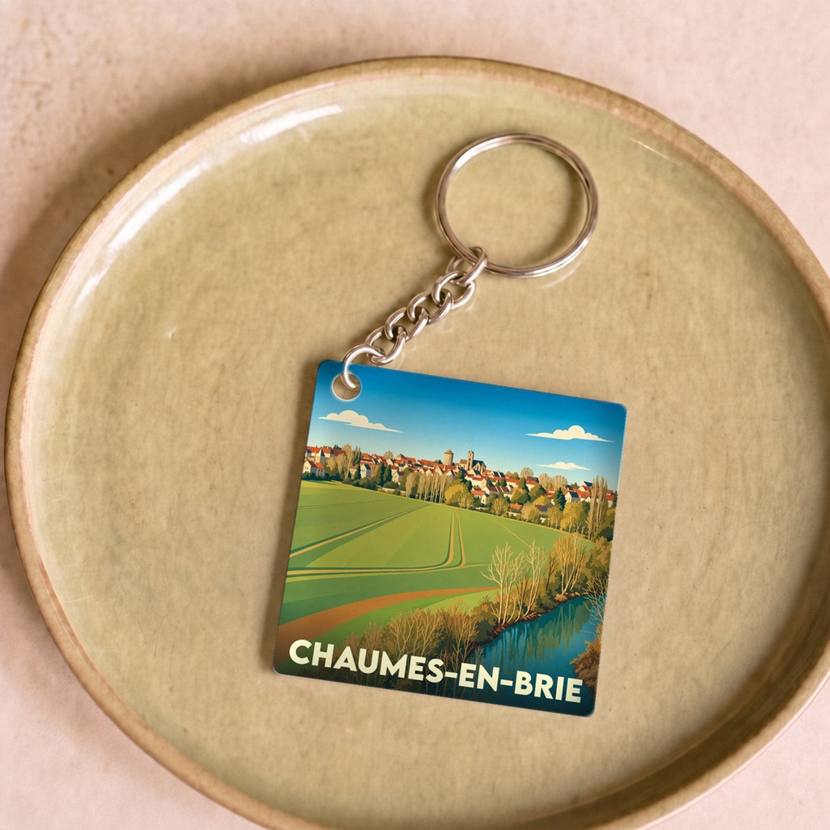 Porte-clés souvenir de la ville de Chaumes-en-Brie avec une illustration stylisée de son paysage rural.