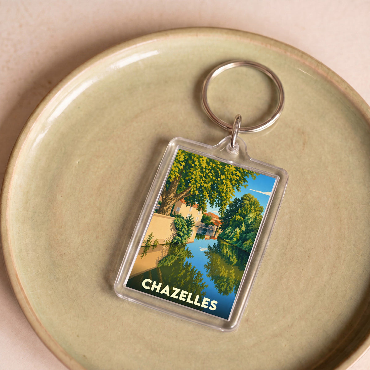 Porte-clés souvenir de la ville de Chazelles avec une illustration stylisée d'un canal arboré.
