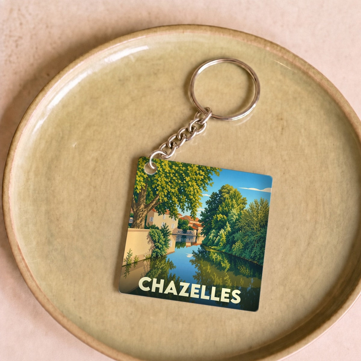 Porte-clés souvenir de la ville de Chazelles avec une illustration stylisée d'un canal arboré.