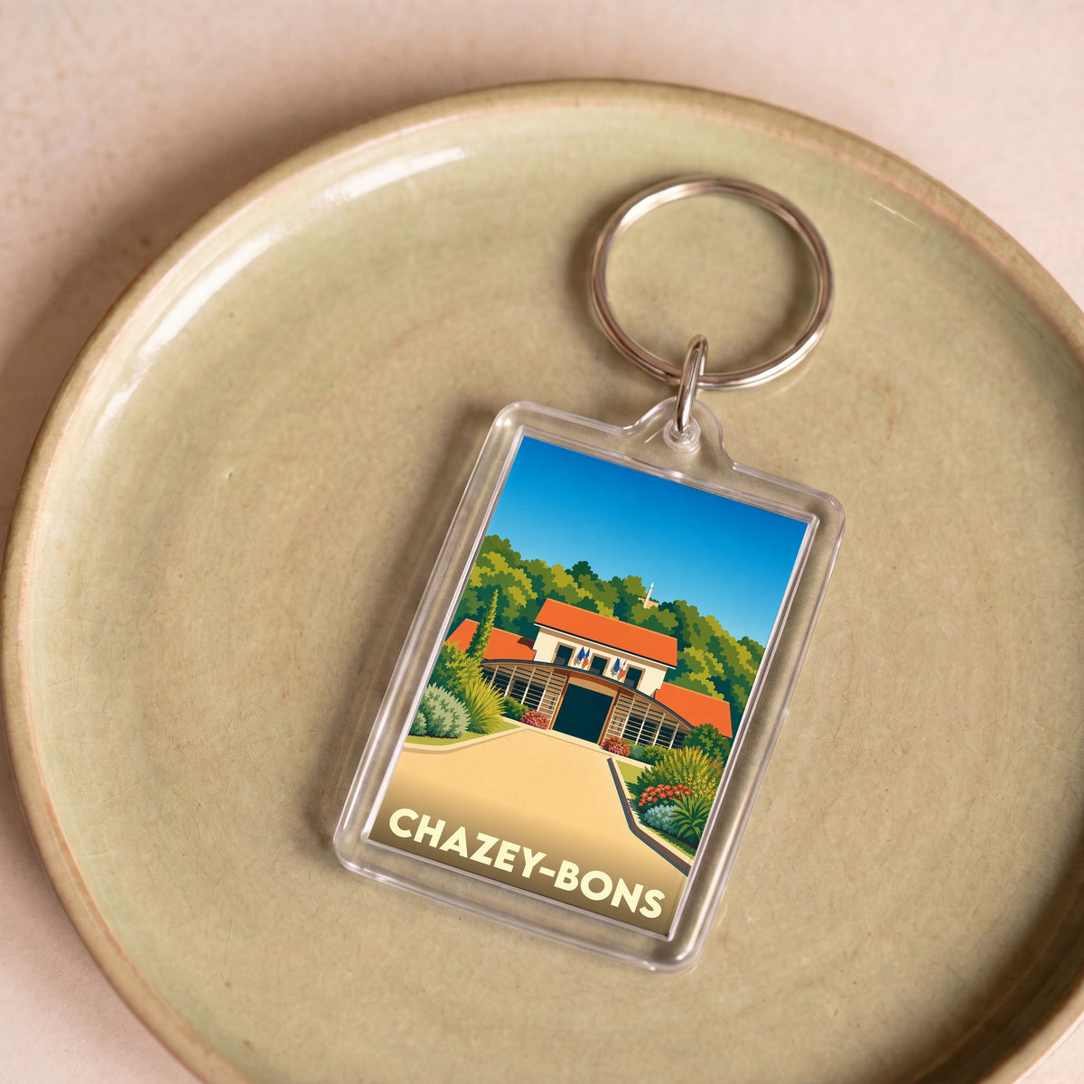 Porte-clés souvenir de la ville de Chazey-Bons avec une illustration stylisée d'un bâtiment local.