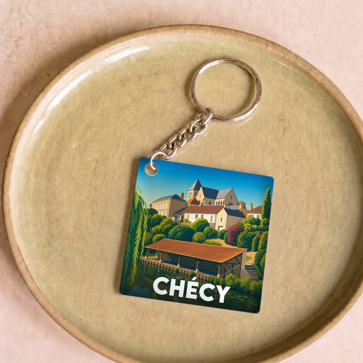 Porte-clés souvenir de la ville de Chécy avec une illustration colorée et stylisée.