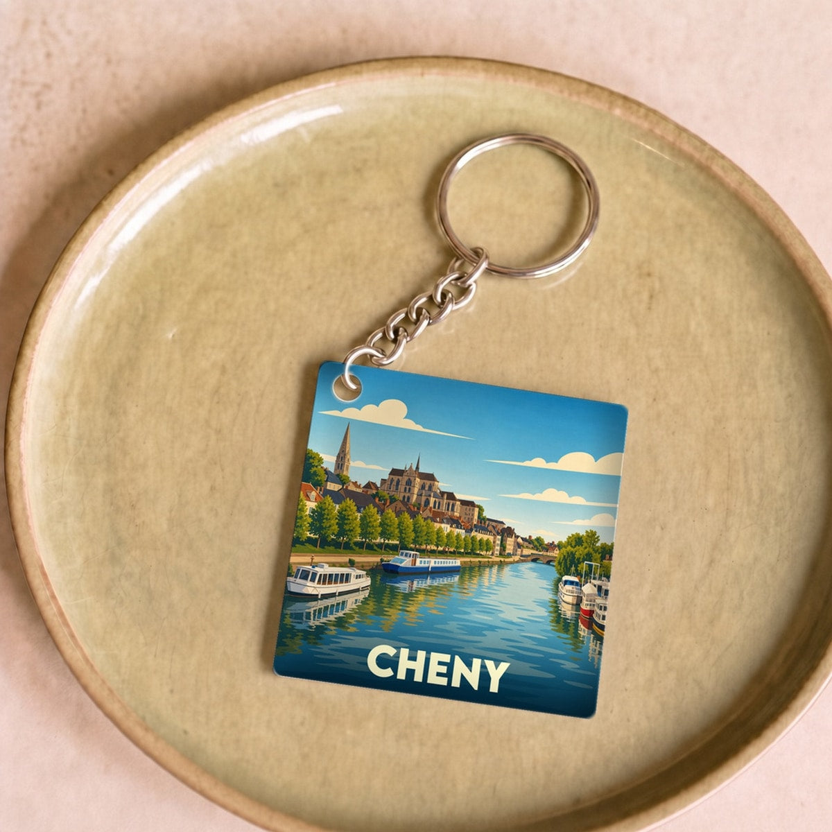 Porte-clés souvenir de la ville de Cheny avec une illustration stylisée d'un bord de rivière.