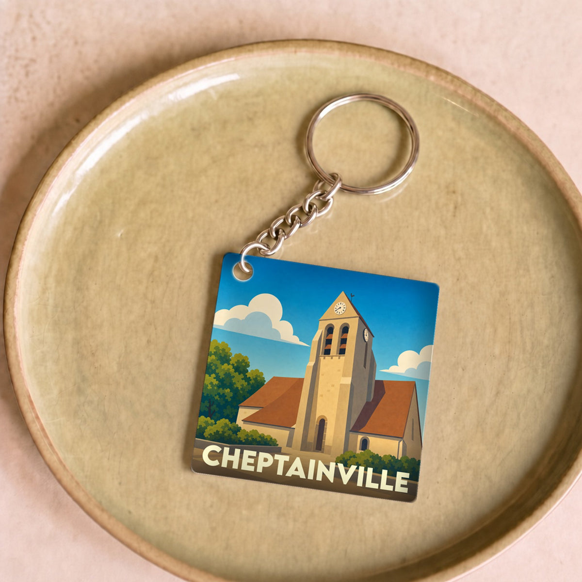 Porte-clés souvenir de la ville de Cheptainville avec une illustration stylisée de son église.