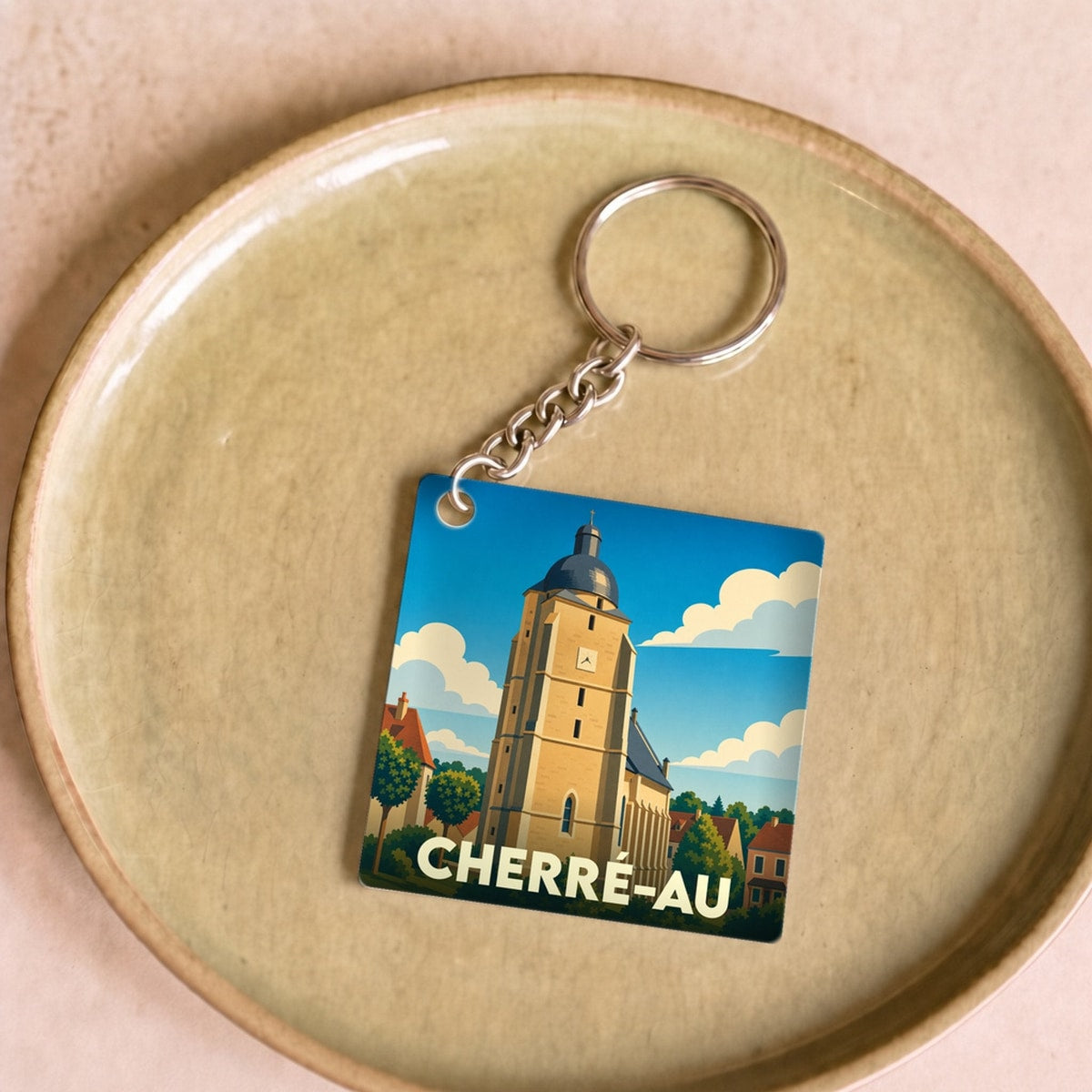 Porte-clés souvenir de la ville de Cherré-Au avec une illustration stylisée de son église.
