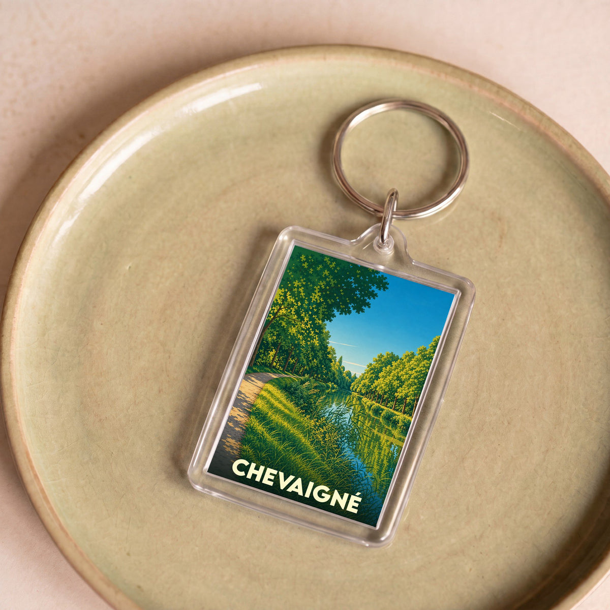 Porte-clés souvenir de la ville de Chevaigné avec une illustration stylisée d'un paysage de canal.