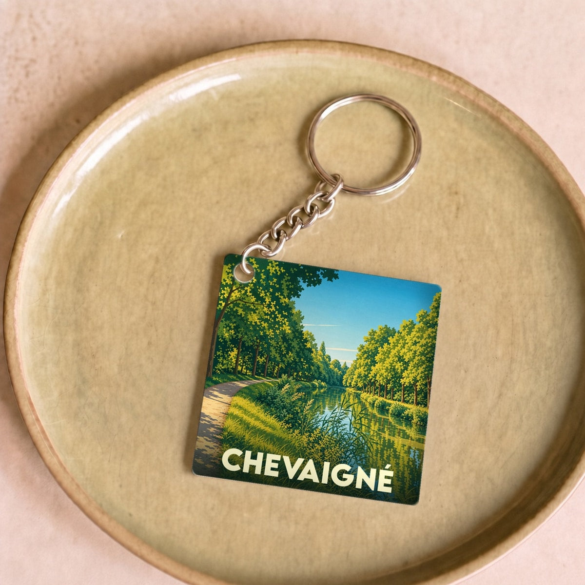 Porte-clés souvenir de la ville de Chevaigné avec une illustration stylisée d'un paysage de canal.