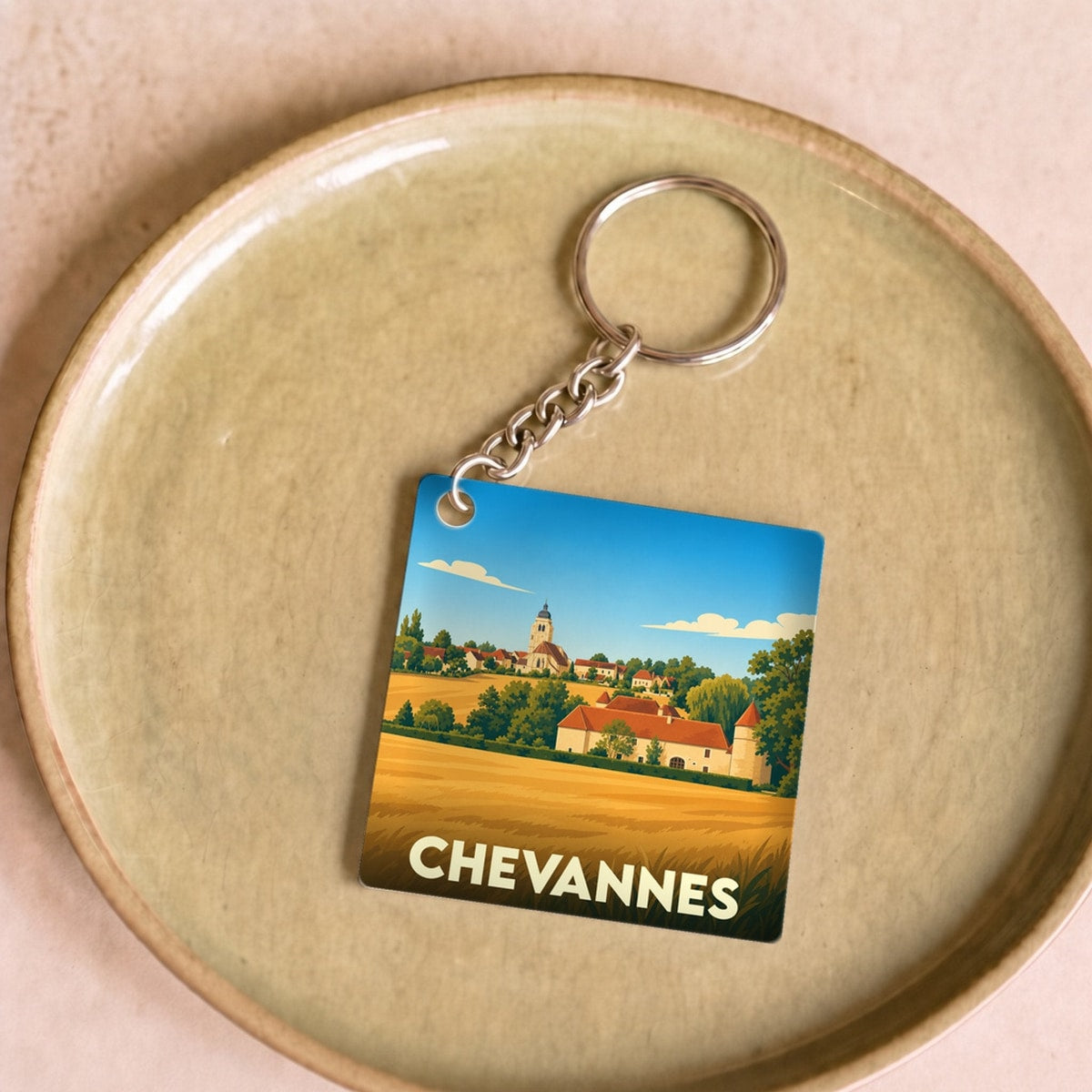 Porte-clés souvenir de la ville de Chevannes avec une illustration stylisée de son paysage et de son église.